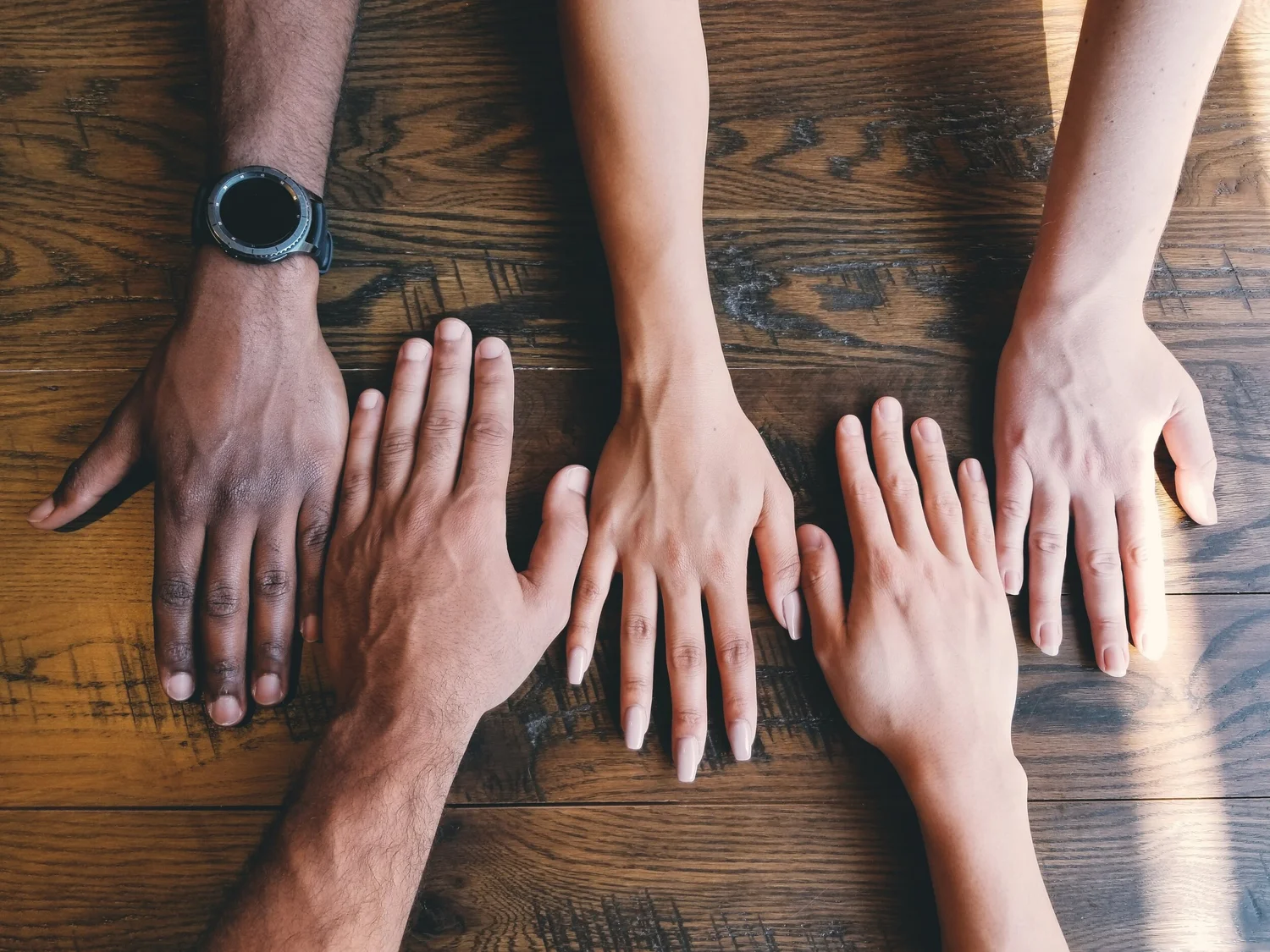 Group of people hugging each other. No faces. Photo by Helena Lopes on Unsplash